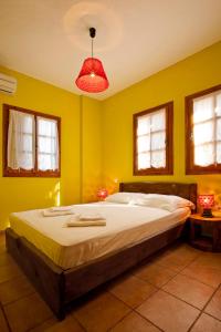 a bedroom with a large bed with yellow walls at Victoria's Guesthouse in Damouchari
