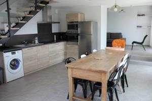 uma cozinha com uma mesa de madeira e cadeiras numa cozinha em La Maison de Léobin em Véranne