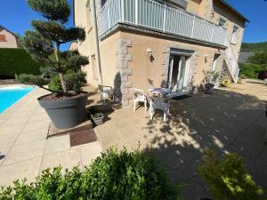 eine Terrasse mit einem Tisch und Stühlen neben einem Haus in der Unterkunft Au coeur du Gévaudan appartement de plain pied in Marvejols