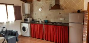 uma cozinha com uma máquina de lavar roupa e uma cortina vermelha em La Hacienda Del Campo em Potes