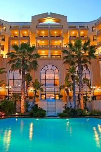 a resort with a swimming pool in front of a building at Corinthia St George's Bay in St. Julianʼs