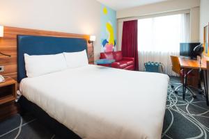 a hotel room with a large bed and a desk at ibis Styles Birmingham NEC & Airport in Bickenhill