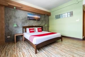 ein Schlafzimmer mit einem Bett mit zwei roten Kissen in der Unterkunft OYO 1118 KL boutique Hotel in Krabi