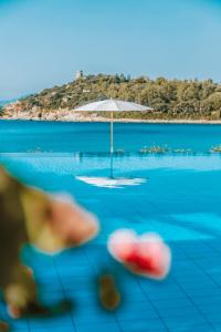a view of a swimming pool with an umbrella at Hotel La Bitta - Bovis Hotels in Àrbatax