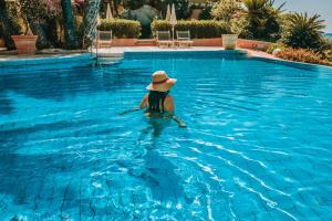 a woman in a hat in a swimming pool at Hotel La Bitta - Bovis Hotels in Àrbatax