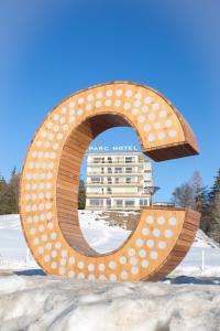 a large metal sign with a hotel in the background at Grand Hôtel du Parc in Crans-Montana