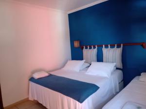 Habitación con 2 camas y pared azul en Pousada Manhã Dourada, en Arraial d'Ajuda