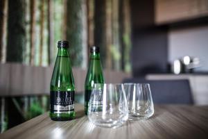 twee groene flessen en glazen op een houten tafel bij Hotel Mazurek in Koło