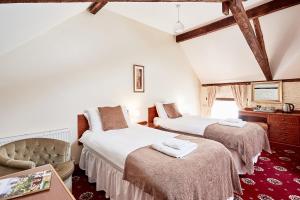 a bedroom with two beds and a chair in a room at The Bateman Arms at Shobdon in Shobdon