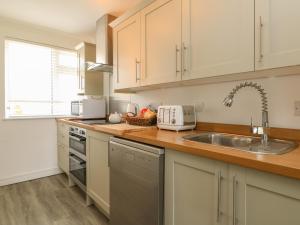 a kitchen with white cabinets and a sink at 2 Europa Court in Newquay