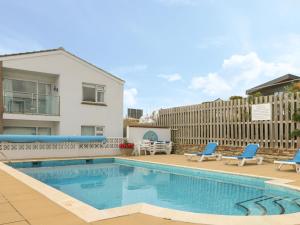 una piscina con due sedie blu e una casa di 2 Europa Court a Newquay