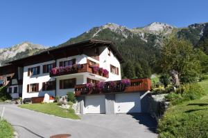 a white building with flowers on the balconies of it at Hof Kurzamann in Klösterle am Arlberg
