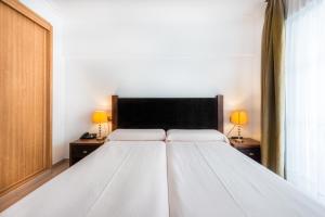 a white bed in a room with two lamps at Toboso Apar - Turis in Nerja