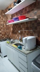 uma cozinha com um lavatório e alguns pratos nas prateleiras em BEIRA MAR DE JATIÚCA em Maceió