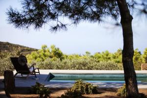 una persona sentada en una silla junto a una piscina en Tenuta Borgia, en Pantelleria
