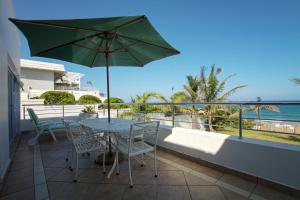 een patio met een tafel en stoelen en een parasol bij Seashelles Self-catering Apartment in Durban
