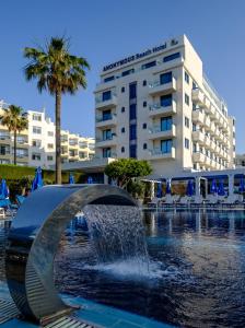 a fountain in front of a hotel with a building at Anonymous Beach Hotel (Adults 16+) in Ayia Napa