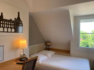 a bedroom with a bed and a desk and a window at Hotel Anne De Bretagne BLOIS in Blois