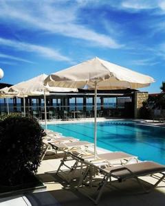 un grupo de sillas y una sombrilla junto a la piscina en Nektar Beach Hotel, en Stalós