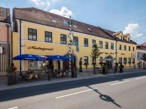 a yellow building with blue umbrellas on a city street at Hotel Bayrischer Löwe in Osterhofen