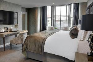 a bedroom with a bed and a desk and a television at The Bold Hotel; BW Signature Collection in Southport