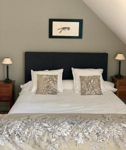 a bedroom with a large white bed with two pillows at La Maison Les Mimosas in Le Minihic-sur-Rance