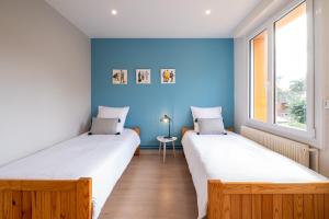 2 camas en una habitación con paredes azules en Appartement La Rafale - accès privé plage - jardin - arrivée autonome, en Gravelines