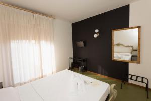 a bedroom with a white bed and a mirror at Mami Sabaudia Hotel in Sabaudia