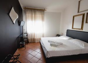 a bedroom with a bed with white sheets and a window at Mami Sabaudia Hotel in Sabaudia