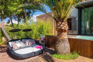 una cama sentada junto a una palmera junto a una piscina en Villa Lares, en Cala Mendia