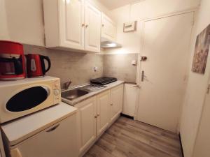 a small kitchen with a microwave and a sink at Superbe studio pour 2 à 20m de la plage - 27 in Canet-en-Roussillon