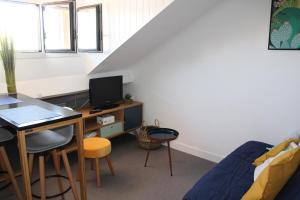Zimmer mit einem Schreibtisch, einem Computer und einem Sofa in der Unterkunft Studio hyper centre avec vue sur les Pyrénées in Saint-Jean-de-Luz