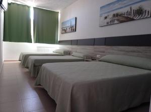 fila de camas en una habitación con cortinas verdes en Hostal Brin, en Monreal del Campo