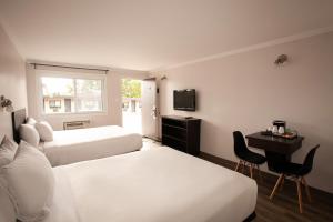 Habitación de hotel con 2 camas, escritorio y TV. en Motel Newstar Laval, en Laval