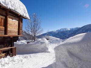 uma pilha de neve ao lado de uma cabana de madeira em Naflerhof em Obertilliach