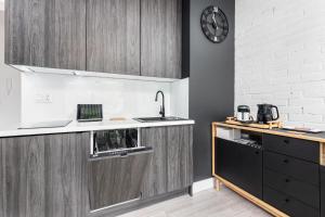 a kitchen with wooden cabinets and a clock on the wall at Apartamenty Solny Brzeg by Renters Prestige in Kołobrzeg