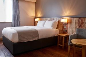 a hotel room with a large bed and a table at The Churchill By Greene King Inns in Royal Wootton Bassett