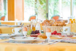einen Tisch mit Eiern und Brot und einen Korb mit Lebensmitteln in der Unterkunft Hôtel A la Vignette - COLMAR-NORD in Saint-Hippolyte