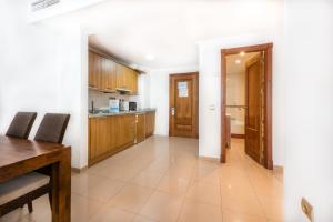 a kitchen with wooden cabinets and a dining table at Toboso Apar - Turis in Nerja