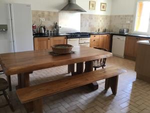 a kitchen with a wooden table and a wooden bench at Maison de la Fontaine in Embres-et-Castelmaure