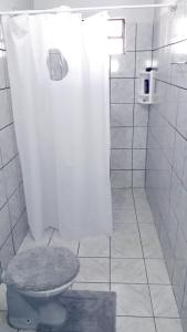 a white bathroom with a toilet and a shower at Hospedagem Domiciliar em Lucas do Rio Verde in Lucas do Rio Verde