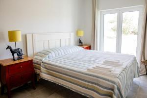 1 dormitorio con 1 cama con manta a rayas y ventana en Casas da Estação, en Marvão