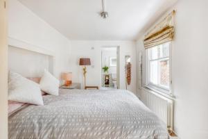 een witte slaapkamer met een groot bed en een raam bij Pass the Keys - Beautiful stylish flat in South West London in Londen
