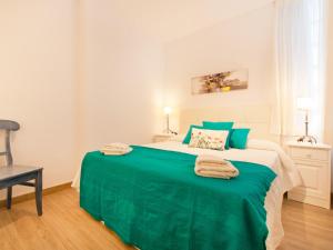 una camera da letto con un grande letto verde con asciugamani di Apartment Oiza Classic, at Alcudia Beach a Port d'Alcudia
