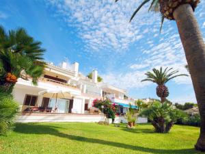 een wit huis met palmbomen en een gazon bij Apartment Vida Sana with Sea Views and Garden in Port d'Alcudia