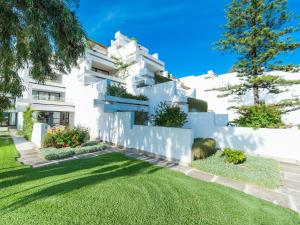 a white building with a green yard at Apartment Oiza Sand Castle 15 at Alcudia Beach, WIFI and aircon in Alcudia