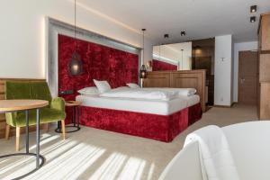 una camera con un grande letto con una parete rossa di Diamant Spa Resort a Santa Cristina in Val Gardena