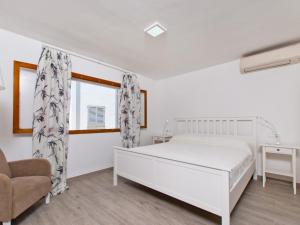 a white bedroom with a bed and a chair at Apartment Mar del Plata in Alcudia beach in Alcudia