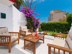 a patio with a table and chairs and purple flowers at Apartment Mar del Plata in Alcudia beach in Alcudia