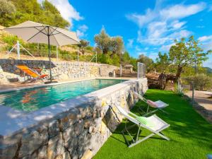 a pool with two lawn chairs and an umbrella at Villa Mancor Pool & Mountain Views in Mancor del Valle